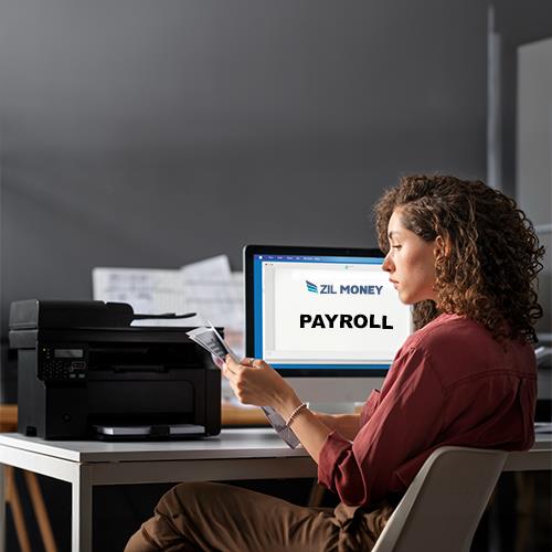 A Woman Sitting at a Desk with the Best Payroll for Small Business in Front of Her