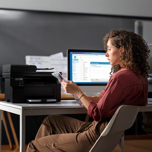 A Woman Sitting at a Desk Using an HP Printer to Print Business Checks