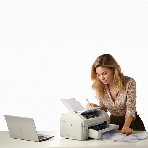 A Woman Is Sitting at a Desk with a Printer, and Cheap Checks Order Using Her Laptop