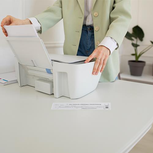 A Woman Is Putting Paper into a Printer to Print Her Paper Checks