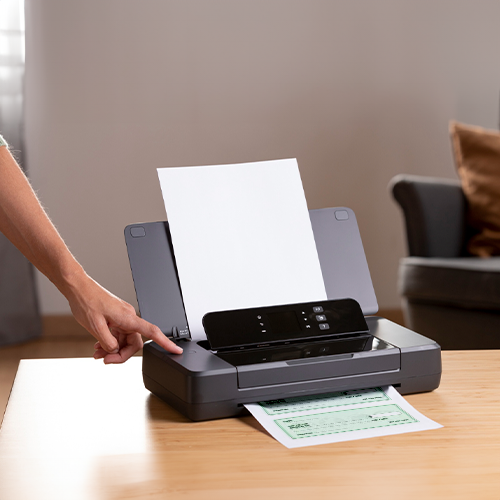 A Person Is Putting Paper into a Printer to Create Checks Online.