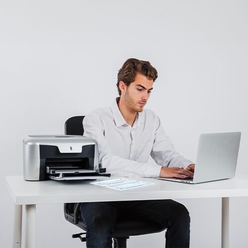 Using a Laptop Printer, a Man Sits in a Chair. Currently, He's Using Software to Print Bank Check