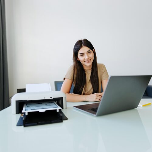 A Woman Preparing to Print Bank Checks at a Table with a Laptop and Printer.