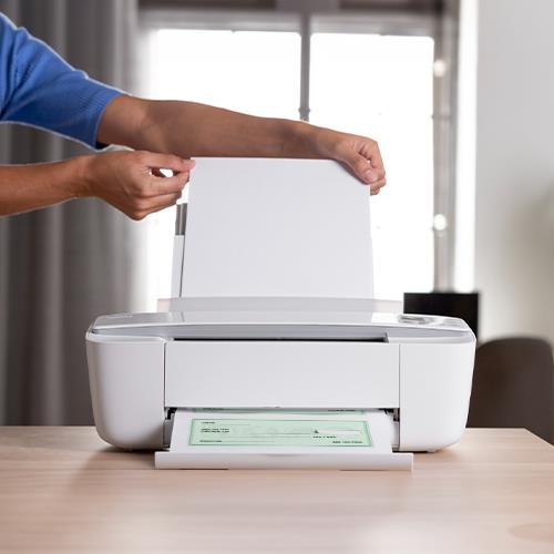 A Man Putting Paper into a Printer to Print Business Checks At Home Free