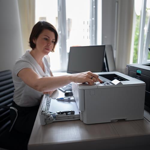 A Woman Using a Printer to Engage in Check Writing Online Free, with a Check Visibly Printing Out.