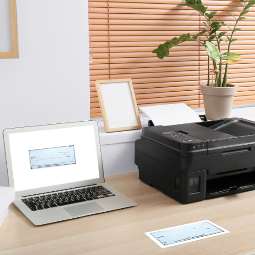 A Laptop and a Printer on a Desk. Instantly, the Printer Prints Checks Online