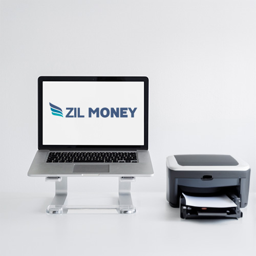 A Laptop on a Stand Showcasing the Secure32 Alternative Logo Beside a Printer Situated on a White Desk Against a Plain Background.