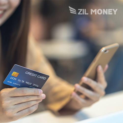 A Woman Is Holding a Credit Card and Using a Smartphone, Possibly Making an Online Purchase. the Focus Is on the Card and Phone, Seamless and Secure Credit Card Payments For Small Business