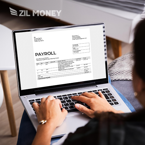 A Person Sits on a Couch Using a Laptop Displaying Payroll Checks, Unlocking Potential by Choosing the Best Payroll for Small Business.