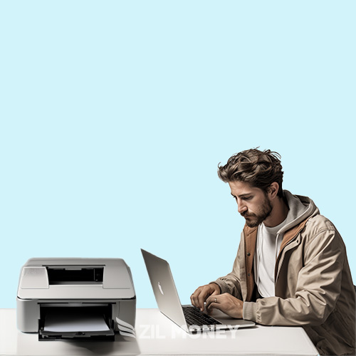 Man Focused on Work at His Laptop, Using a Check Printing Solution, with a Printer Beside Him on a Minimalist Blue Background