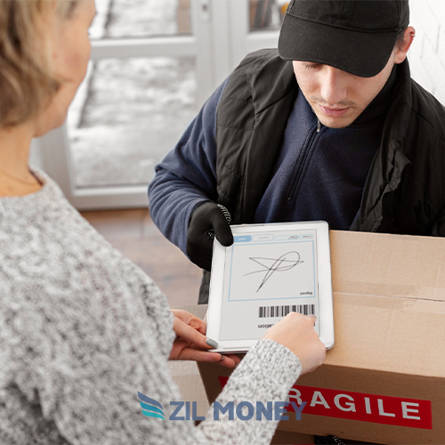 A Delivery Man in a Black Cap and Jacket Using a Digital Tablet to Collect a Signature from a Woman for a Package Delivery Indoors, Labeled Sending Check By Mail