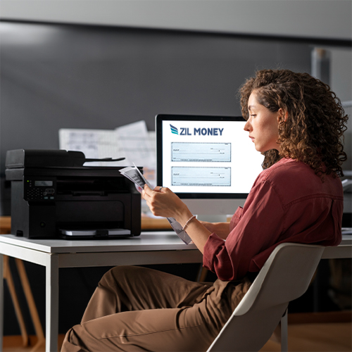 From Pre-Printed Hassles to Online Efficiency: Write Checks for Free. Woman Sitting at Desk Examines Document Next to Printer.