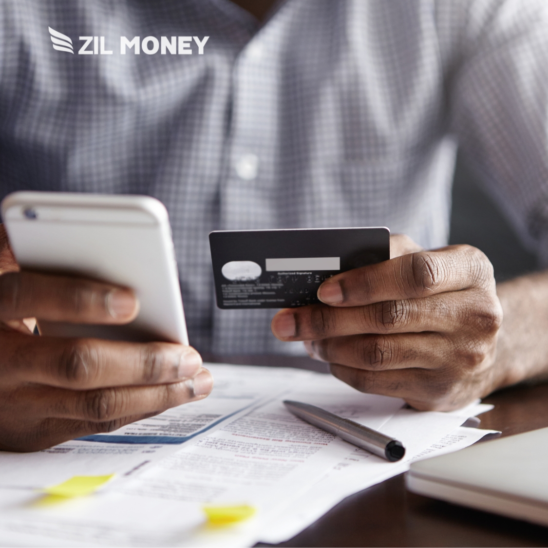 From Transactions to Rewards: Exploring the Value of Credit Card to Pay Bill. a Person Sitting at a Desk Holding a Smartphone in One Hand and a Credit Card in the Other.