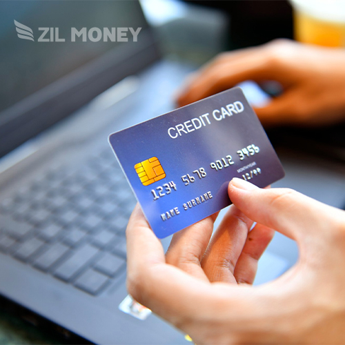 A Man Holding a Laptop and Credit Card. He Is Looking for the Most Convenient Way to Pay Rent with Credit Card
