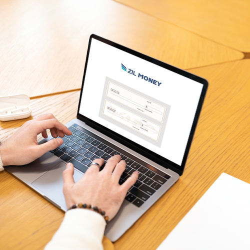 A Man Types on a Laptop. He Is Writing a Personal Check