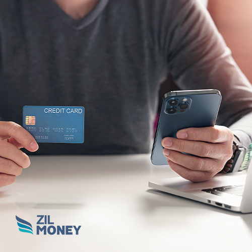 A Hand Holding A Credit Card And A Smartphone Paying Vendors. Managing Expenses with American Express Credit Card Payment