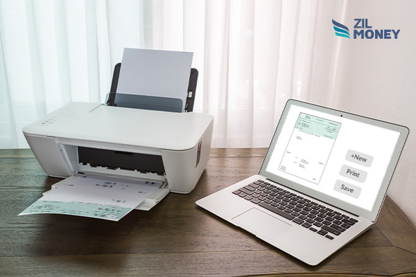 A Laptop Displaying the Online Printable Checks Next to a Printer with Printed Checks For Payments