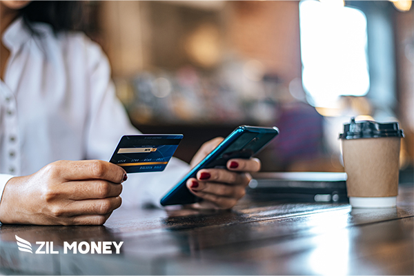 A Person Holding a Credit Card And A Smartphone Effortlessly Process ADP Payroll By Credit Card Payments Easily for Your Business