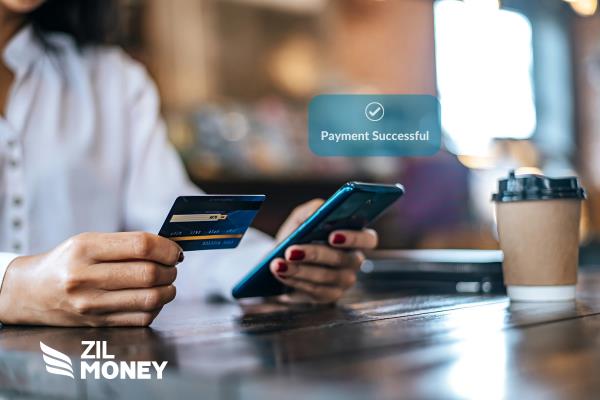 A Person Holding a Credit Card And Working On a Phone Making American Express Credit Card Payment.