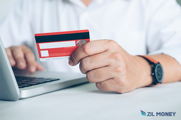 A Person Holding a Credit Card And Working On a Laptop Pay SuperWorks Payroll By Credit Card and Earn Rewards