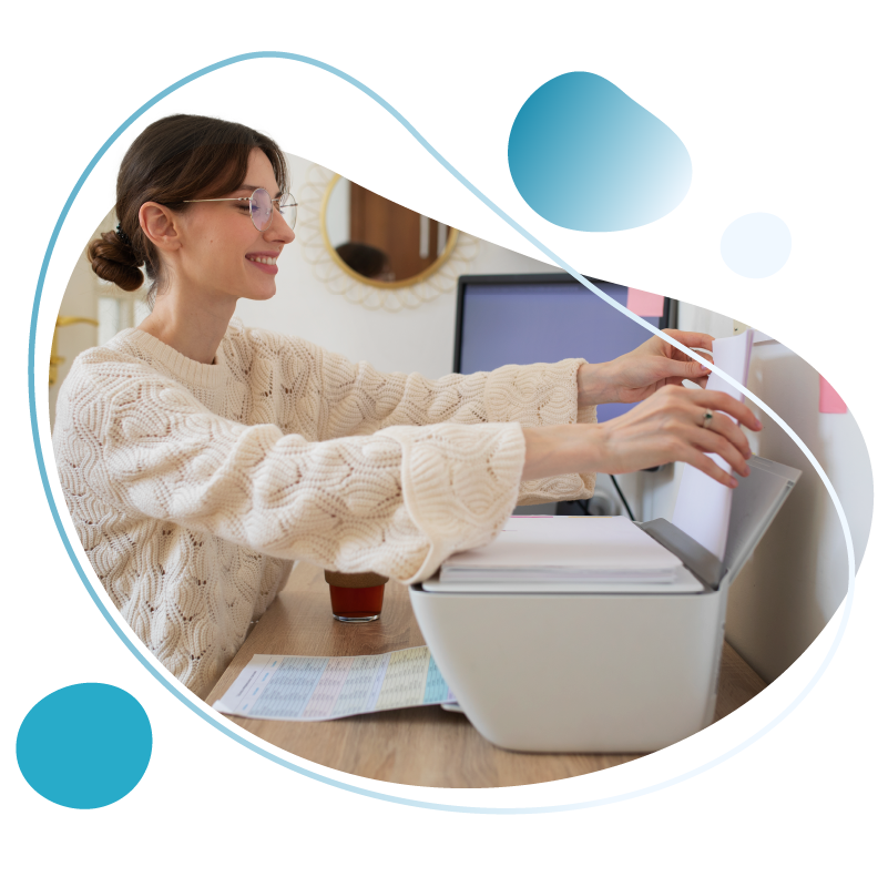 A woman printing checks on blank check stock from her desk. 