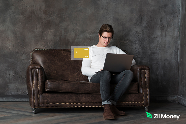 Man sitting on a leather couch using a laptop with an overlay graphic of virtual cards for secure online payments.