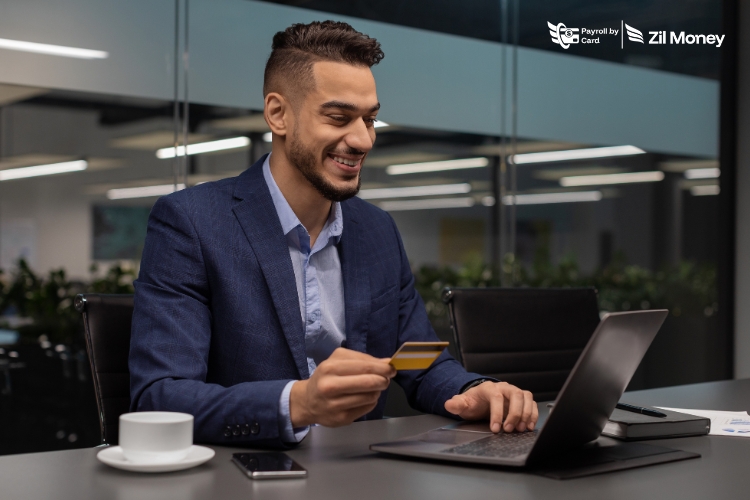A business professional using a laptop and credit card to run Payroll by Card, showing quick and secure employee payments.