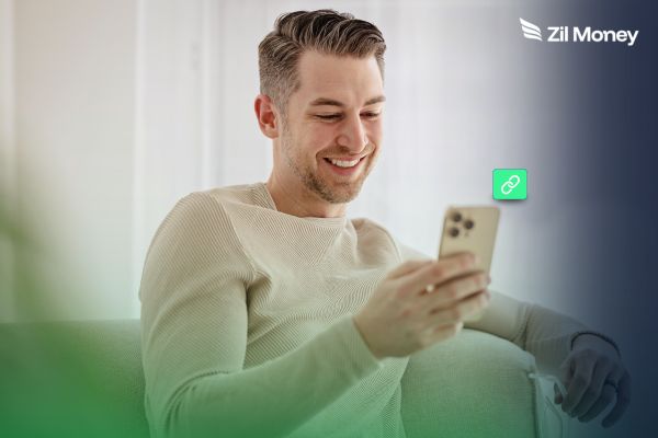 Invoice Payment Link Simplifying Real Estate Collections A smiling man uses a smartphone with an invoice payment link icon, showing payment convenience.
