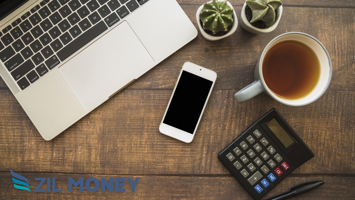 Business Wallet for Vendor Payments – Zil Money Office desk flat lay with laptop, phone, and calculator representing a Zil Money business wallet used to pay vendors