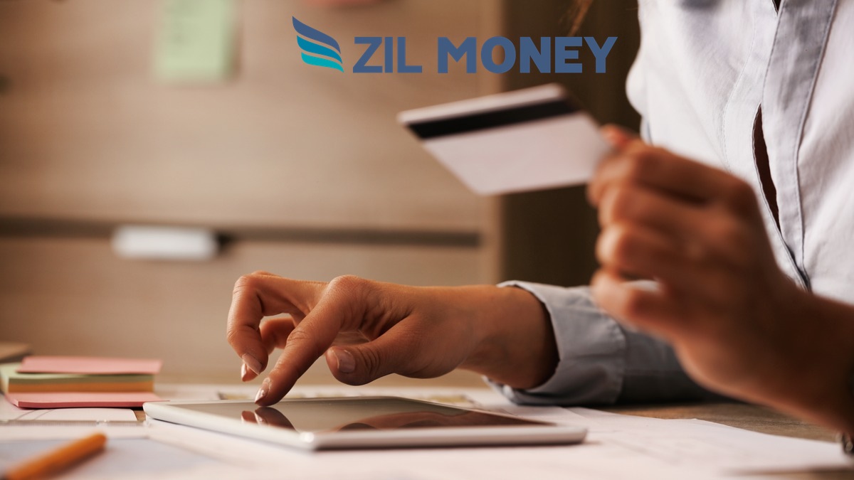 Credit Card Payments App Security Certifications Hero Person holding a credit card and tablet at a desk, illustrating a Zil Money credit card payments app