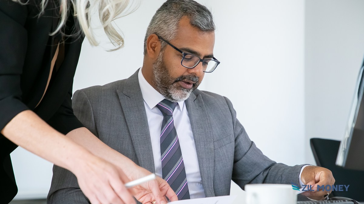 Nonprofit finance director reviewing financial documents with a colleague at the office to guard against fraud